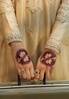 a woman with her hands painted in hendi and holding a piece of silver luggage