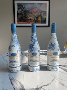 three blue and white bottles sitting on top of a table next to a bowl filled with fruit