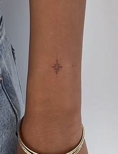 a woman's arm with a small cross tattoo on the left side of her wrist