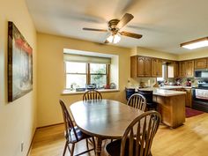 a kitchen and dining room with wood flooring, ceiling fan, table and chairs