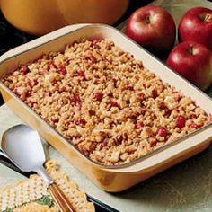 an apple crisp is in a baking dish next to apples and crackers on the table