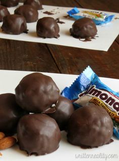 there are chocolate balls and almonds on the table next to some candy bar wrappers