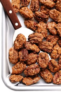 a tray filled with fried food next to a wooden spoon