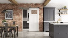 an open kitchen with brick walls and gray cabinets, along with a dining room table