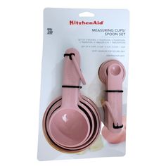 pink measuring cups and spoons are packaged in a package for sale on a white background