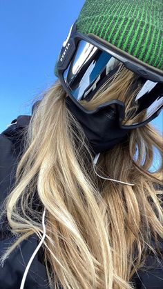 a woman wearing ski goggles and a green knitted hat on top of her head