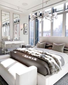 a large white bed sitting in a bedroom next to tall windows