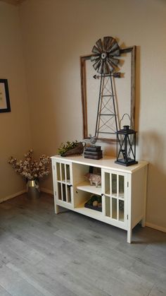 a living room with a windmill on the wall next to a book shelf and vase