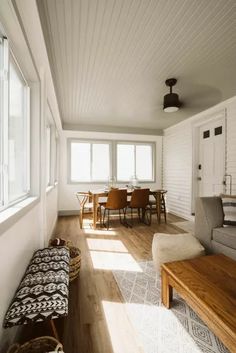 a living room filled with furniture next to a wooden table and chair on top of a hard wood floor