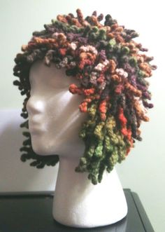 a white mannequin head wearing a multicolored knitted hat on top of a table