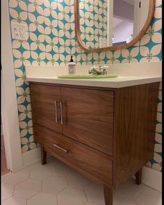 a bathroom with a sink, mirror and wallpaper in the background that has circles on it