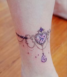 a woman's foot with a heart shaped clock and chain on the ankle tattoo