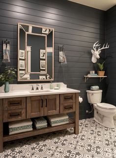 a bathroom with a sink, toilet and deer head on the wall above it's mirror