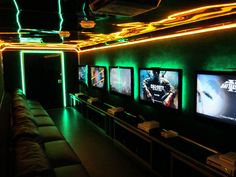 a room filled with lots of tvs and couches covered in neon lights,