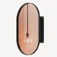 an oval mirror mounted to the side of a wall with a light bulb hanging from it