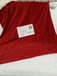 a red blanket sitting on top of a white bed