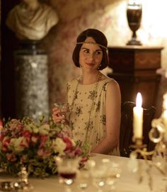 a woman sitting at a table with flowers and candles