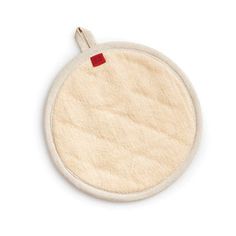 a white round pot holder with a red tag on the front and back of it