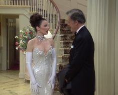 a man in a tuxedo talking to a woman in a dress