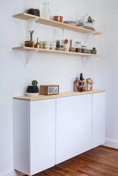 a kitchen with white cabinets and wooden shelves