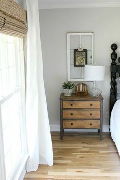 a bed room with a neatly made bed and a dresser next to a large window