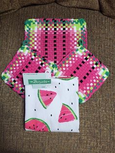 two pieces of cloth with watermelon designs on them are sitting on a couch