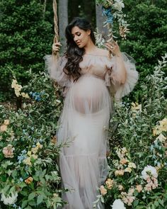 a pregnant woman in a dress holding a flower swing