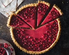 a tart topped with pomegranate on top of a table next to silverware