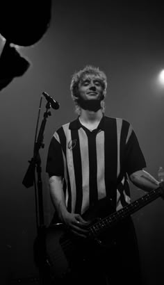 a man standing in front of a microphone holding a guitar