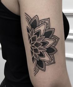 a woman's arm with a black and white flower tattoo on the left forearm