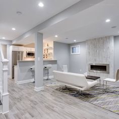 a living room filled with furniture and a fire place next to a kitchen on top of a hard wood floor