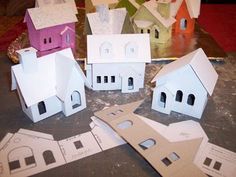 several paper houses sitting on top of a table next to cut out pieces of paper