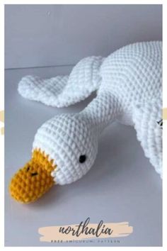 a crocheted white duck laying on top of a table