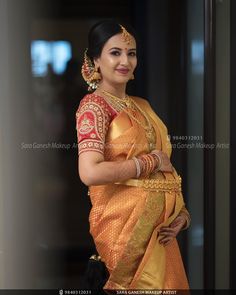 a woman in an orange and gold sari is standing with her hands on her hips