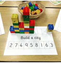 a table topped with legos and building blocks on top of a white sheet that says build a city