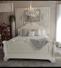 a white bed sitting in a bedroom next to a chandelier