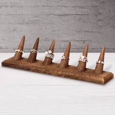 six rings are placed on top of a wooden ring holder that is sitting on a white table