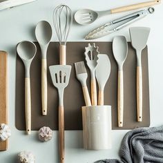 kitchen utensils laid out on a cutting board with wooden spoons and spatulas