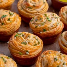 many small pastries are sitting on a baking sheet with some sauce in the background