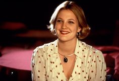 a woman sitting in front of a table wearing a white shirt and black earrings with polka dots on it