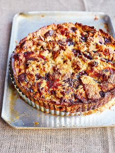 a pie sitting on top of a metal pan covered in toppings and crumbs