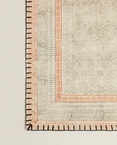 an orange and white rug with fringes on the bottom, in front of a wall