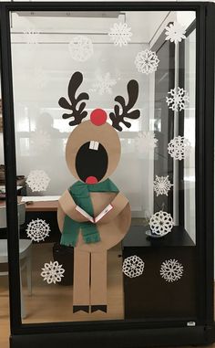 a cardboard reindeer is standing in front of a glass case with snowflakes on it