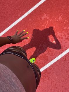 the shadow of a person standing on a tennis court with their hands in the air