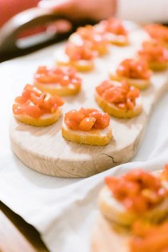 small appetizers with orange sauce on them are sitting on a white cloth next to a cutting board