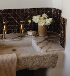 a marble sink with gold faucets and flowers