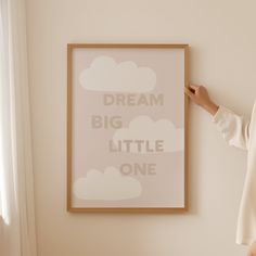 a woman standing next to a poster with the words dream big little one