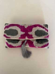 This uzbek  ikat velvet clutch bag with tassel  will make a great birthday gift for the ladies in your family. It combines the modern and traditional, the practical and artistic. Use it as an accessory that will turn heads and make every outfit stand out. The bag is decorated with a fashionable tassel.Put your keys, phone and some special secret things in it and you'll complete that chic look you need for that big occasion or long-awaited party.  The traditional ikat fabric is handwoven with a lot of care in small villages in Uzbekistan. We fell in love with it and wanted to introduce it to you, to the world.  We travel to local artisans, where we carefully select the colours and patterns. Then, we stitch the clutches in our family workshop in Turkey. The heritage of the ikat fabric is uni Rectangular Evening Bag With Tassels, Rectangular Tassel Clutch For Parties, Rectangular Party Clutch With Tassels, Rectangular Tasseled Clutch As Gift, Handmade Rectangular Velvet Clutch, Handmade Velvet Clutch As Gift, Handmade Velvet Clutch As A Gift, Velvet Clutch Bag, Uzbek Ikat