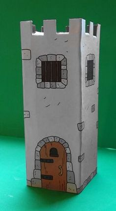 a paper bag shaped like a castle with a door and window on the front, sitting on a green surface