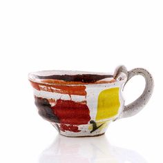 a white cup with red, yellow and green designs on the inside is sitting in front of a white background